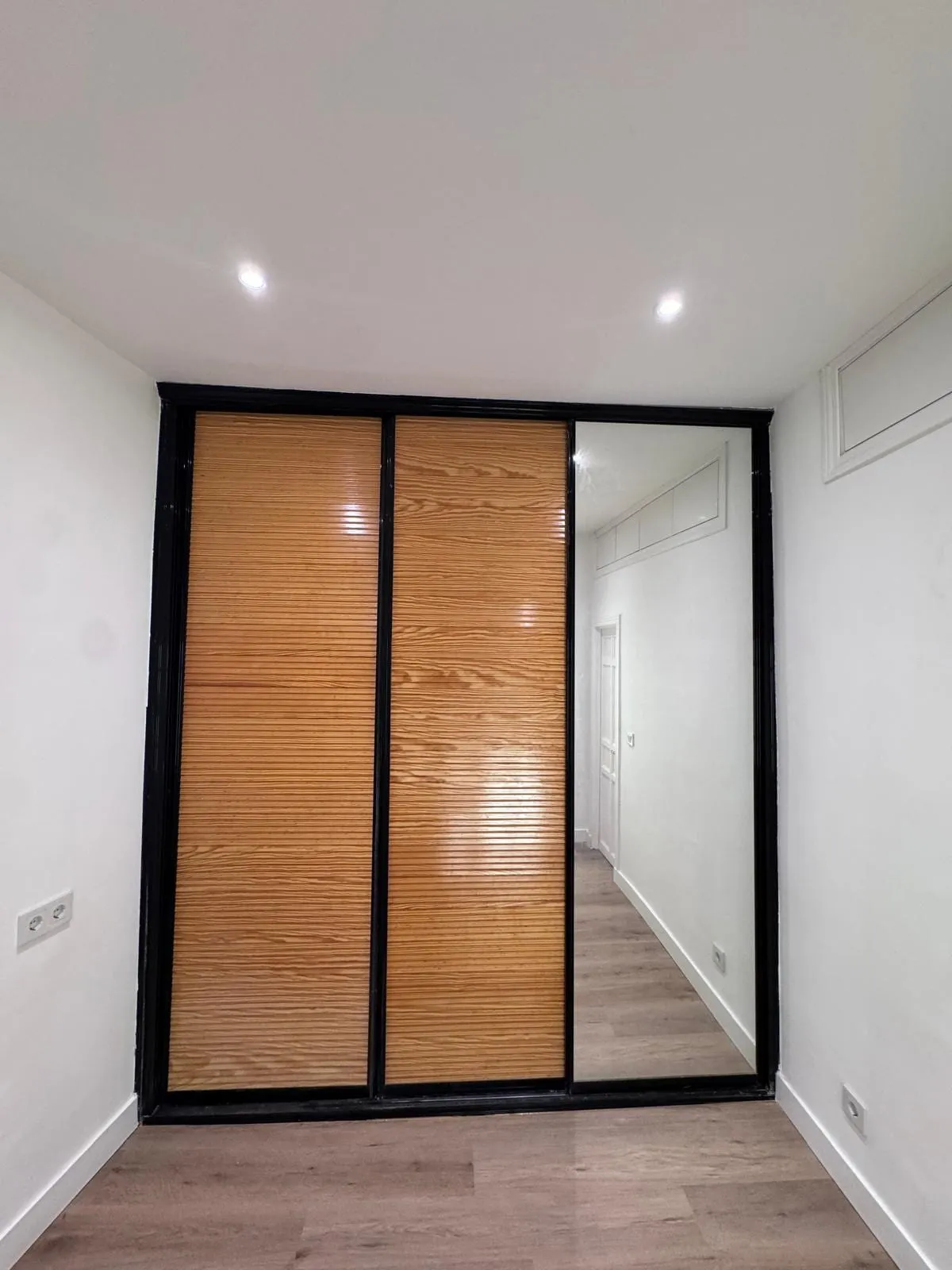 Dormitorio con armario empotrado de madera y paredes recién pintadas