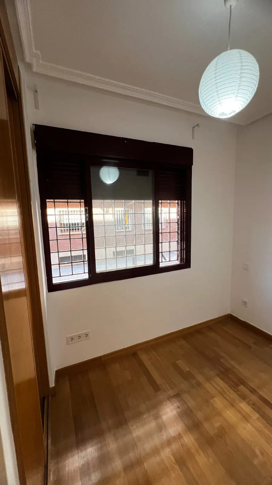 Dormitorio pintado con suelo de madera y lámpara de techo