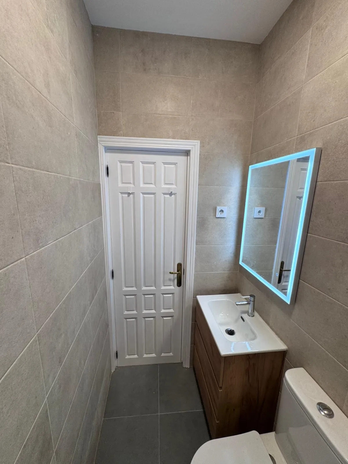 Lavabo con mueble de madera y alicatado en tono piedra